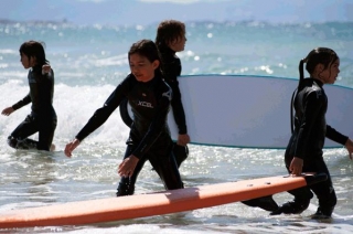varios ninos en el mar con sus tablas de surf